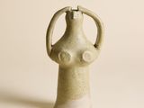 vase en céramique beige posé sur une surface blanche, sur fond blanc