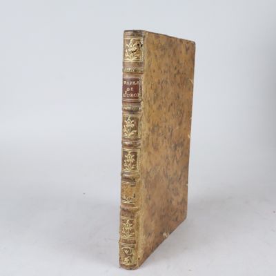 un vieux livre posé sur une table blanche à côté d'un mur blanc
