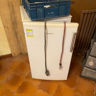 un réfrigérateur blanc sur lequel est posée une corde