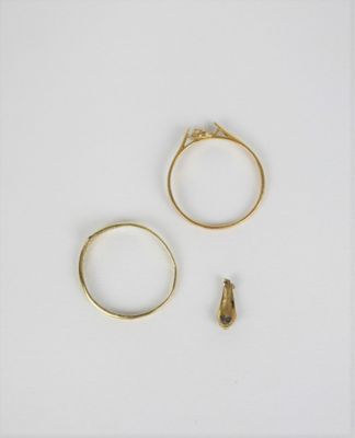 deux bagues en or et une petite bague en diamant posées sur une surface blanche