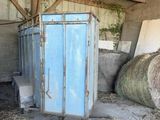 un réfrigérateur bleu au milieu d'une grange, avec du foin par terre