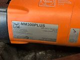 a close up of an orange electric driller on the ground