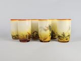 quatre verres ornés de motifs jaunes et orange sont alignés sur une surface blanche