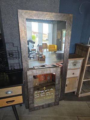 un grand miroir posé par terre à côté d'un bureau