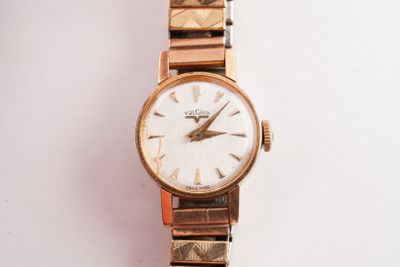 une montre-bracelet en or avec un cadran blanc sur une surface blanche