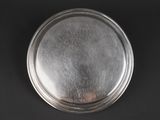 silver plate on a black background with a small hole in the middle
