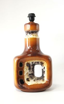 une bouteille marron percée d'un trou, posée sur une surface blanche