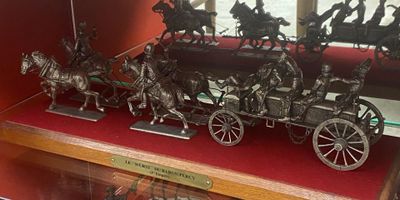 une vitrine contenant plusieurs figurines en bronze représentant des chevaux tirant une calèche