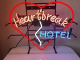 a neon sign that says heart break hotel on a table