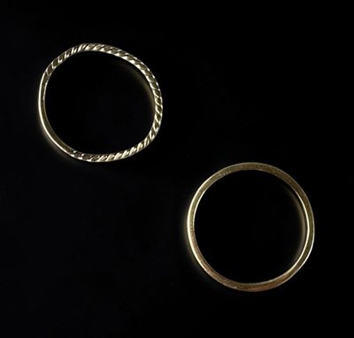 two gold wedding rings on a black background