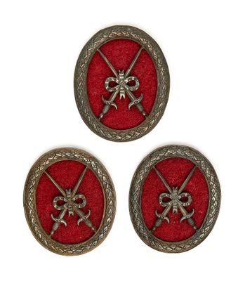 trois boutons métalliques à fond rouge portant deux épées