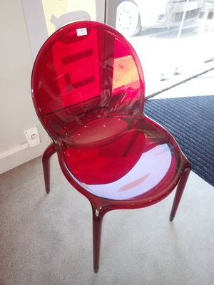 une chaise en plastique rouge posée devant une porte vitrée