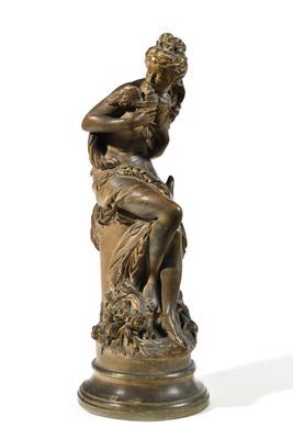 une statue antique en bronze représentant une femme assise sur un rocher