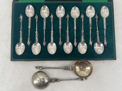 des cuillères en argent et des cuillères à soupe dans une boîte verte posée sur une surface blanche