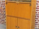 une armoire en bois à deux portes, avec un mur de briques en arrière-plan