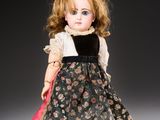 an antique porcelain doll of a woman in a black and pink dress