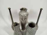three silver vases sitting next to each other on a white surface