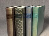 Quatre livres sont alignés sur une surface grise