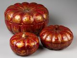 trois citrouilles rouges et dorées posées les unes à côté des autres sur une table