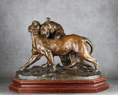 une statue en bronze représentant un lion et une lionne, posée sur un socle en bois