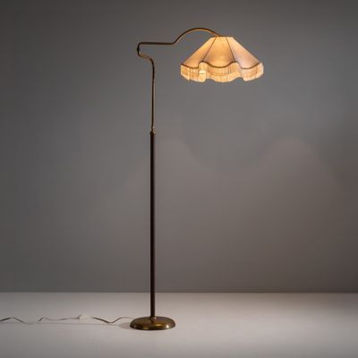 un lampadaire en laiton surmonté d'un abat-jour blanc