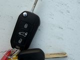 two keys attached to a car key on a white surface