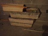 a pile of wood on the ground next to a brick wall