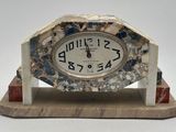 une horloge en marbre posée sur un socle en bois, avec un fond blanc