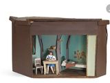 une petite maison de poupées avec une poupée assise à l'intérieur