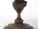 a bronze vase on a pedestal on a white background