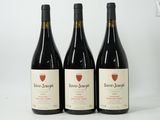 three bottles of wine are lined up on a white surface