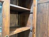 une armoire en bois avec une porte vitrée, placée dans un coin