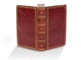 un vieux livre à la couverture rouge posé sur une surface blanche