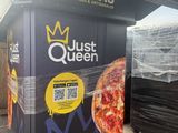 une boîte sur laquelle est représentée une pizza, devant un immeuble
