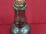 une petite bouteille en verre bouchée d'un bouchon en liège, posée sur un fond rouge
