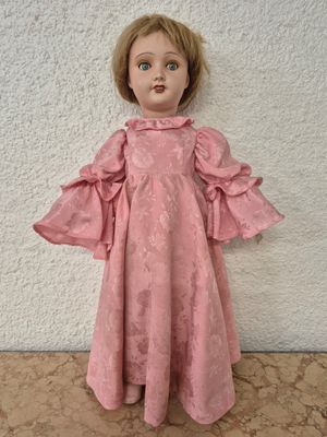 un gros plan d'une poupée vêtue d'une robe rose posée sur une table
