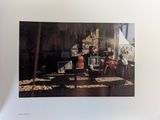 an old photo of a man sitting at a table in front of a painting