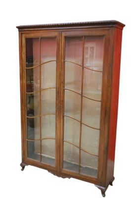 a wooden cabinet with glass doors and a red wall