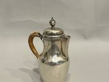 une cafetière ancienne en argent avec une poignée en osier sur fond blanc