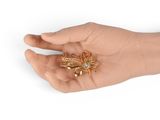 a person holding a gold brooch in their hand