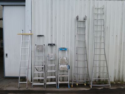 de nombreuses échelles appuyées les unes contre les autres contre un immeuble