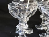 four clear glass goblets sitting on top of a black table