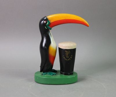 statue of a toucan and a pint of guinness on a table