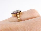 a woman ' s hand holding a gold ring with a purple stone