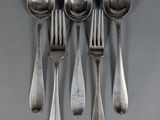 four spoons and a fork are arranged in a row