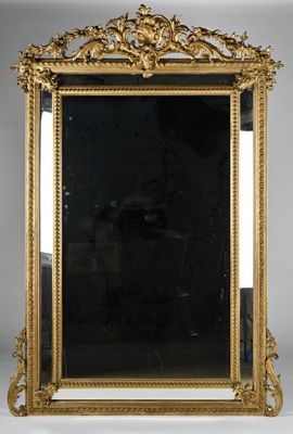 a gold framed mirror sitting on top of a white table