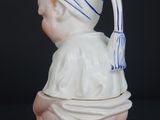 porcelain figurine of a baby sitting on a toilet with a hat on