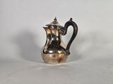 une cafetière ancienne en métal argenté, avec une poignée noire