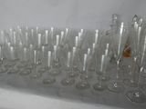 bottles and glasses are lined up on a table in front of a white wall