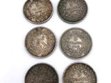 a group of five silver coins sitting on top of a white surface